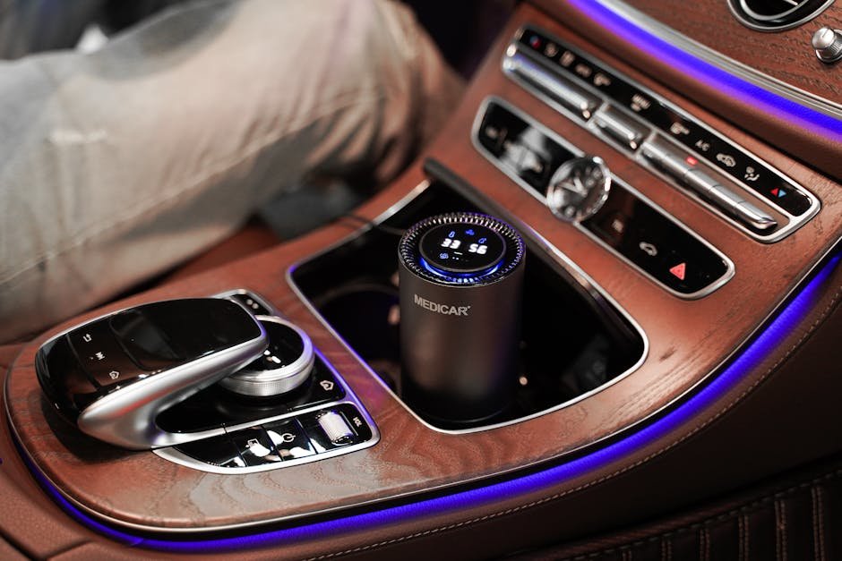 A sleek, portable EV air purifier with a real-time air quality display sitting in the center console of a Tesla