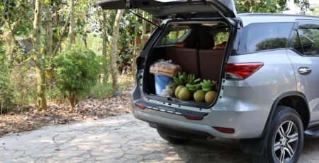 A dual-layer envelope style EV cargo net holding several grocery bags securely against the rear trunk wall of a Tesla Model Y