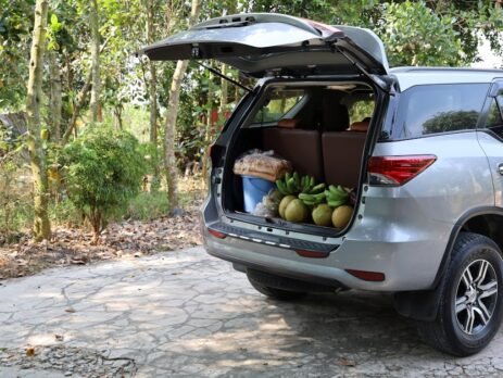 A dual-layer envelope style EV cargo net holding several grocery bags securely against the rear trunk wall of a Tesla Model Y