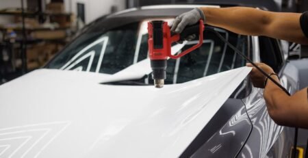 Close-up of a premium, multi-layer EV sunshade with a reflective silver coating being unrolled across the massive glass roof of a modern electric vehicle