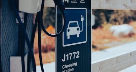 Close-up of a high-quality NACS to J1772 adapter being connected to a non-Tesla electric vehicle charging port at a Destination Charger station