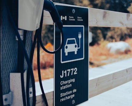 Close-up of a high-quality NACS to J1772 adapter being connected to a non-Tesla electric vehicle charging port at a Destination Charger station